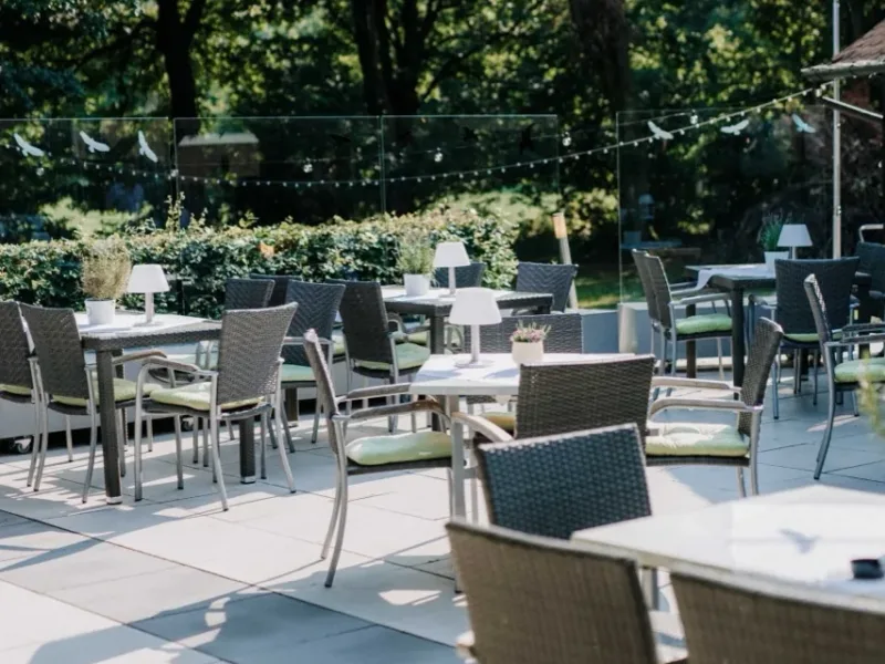 Tische und Sitzplätze auf der Gartenterrasse des Haus Pöpsel unter einem Sonnensegel.